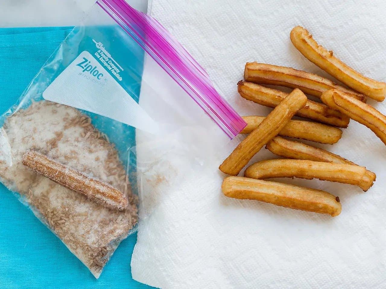 Plain churros on paper towel next to Ziploc bag of cinnamon coconut sugar.