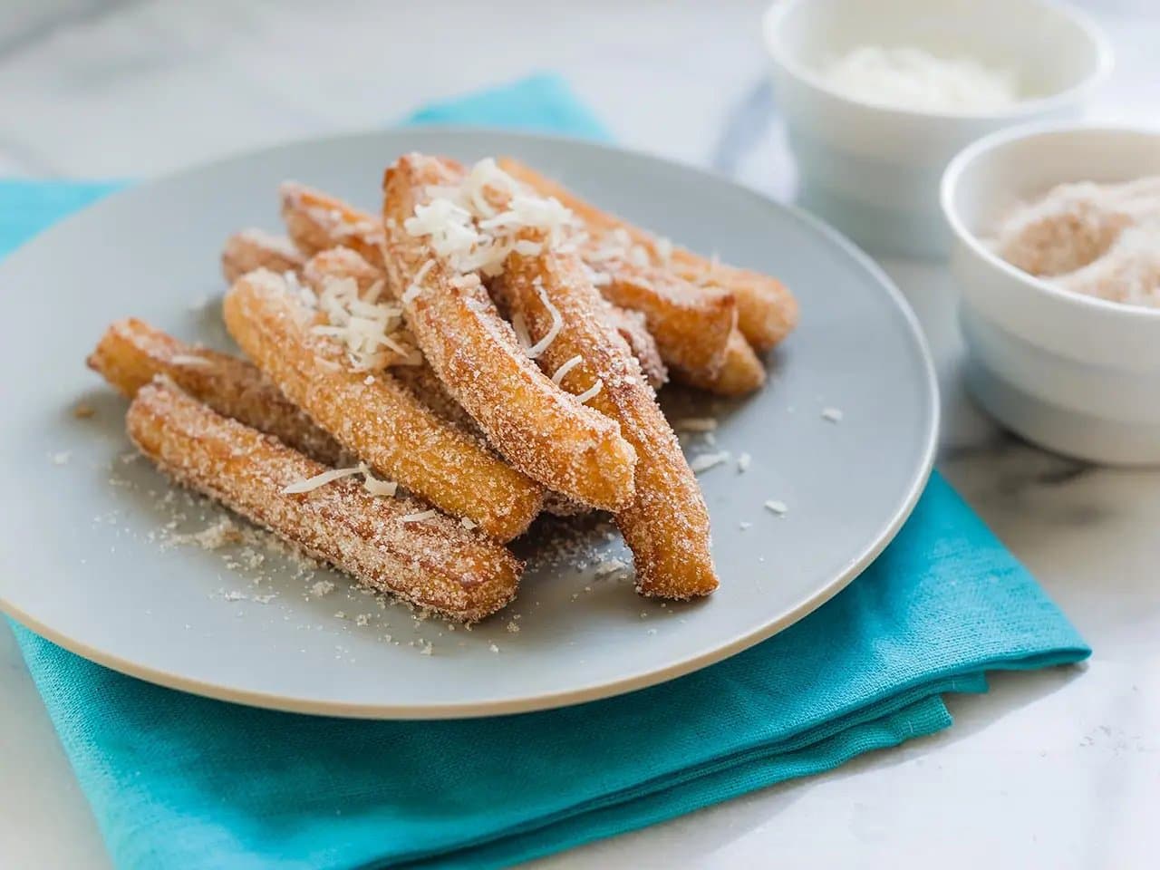 Close up of churros with cinnamon coconut sugar on plate.