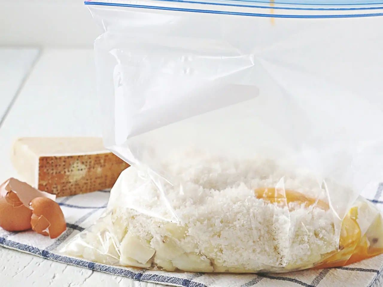 Egg yolks being poured into Ziploc bag of potatoes, flour, cheese, and salt.